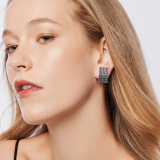 Sterling Silver clip-on earrings in the shape of a slightly curved rectangle, with pretty shiny designs, which embrace the oxidised part of the jewel by Gexist®
